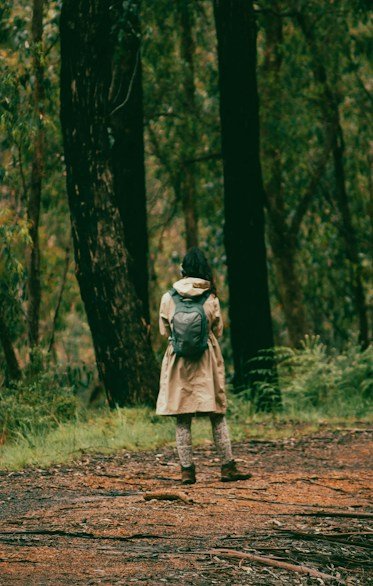 a woman with a backpack walking through a forest