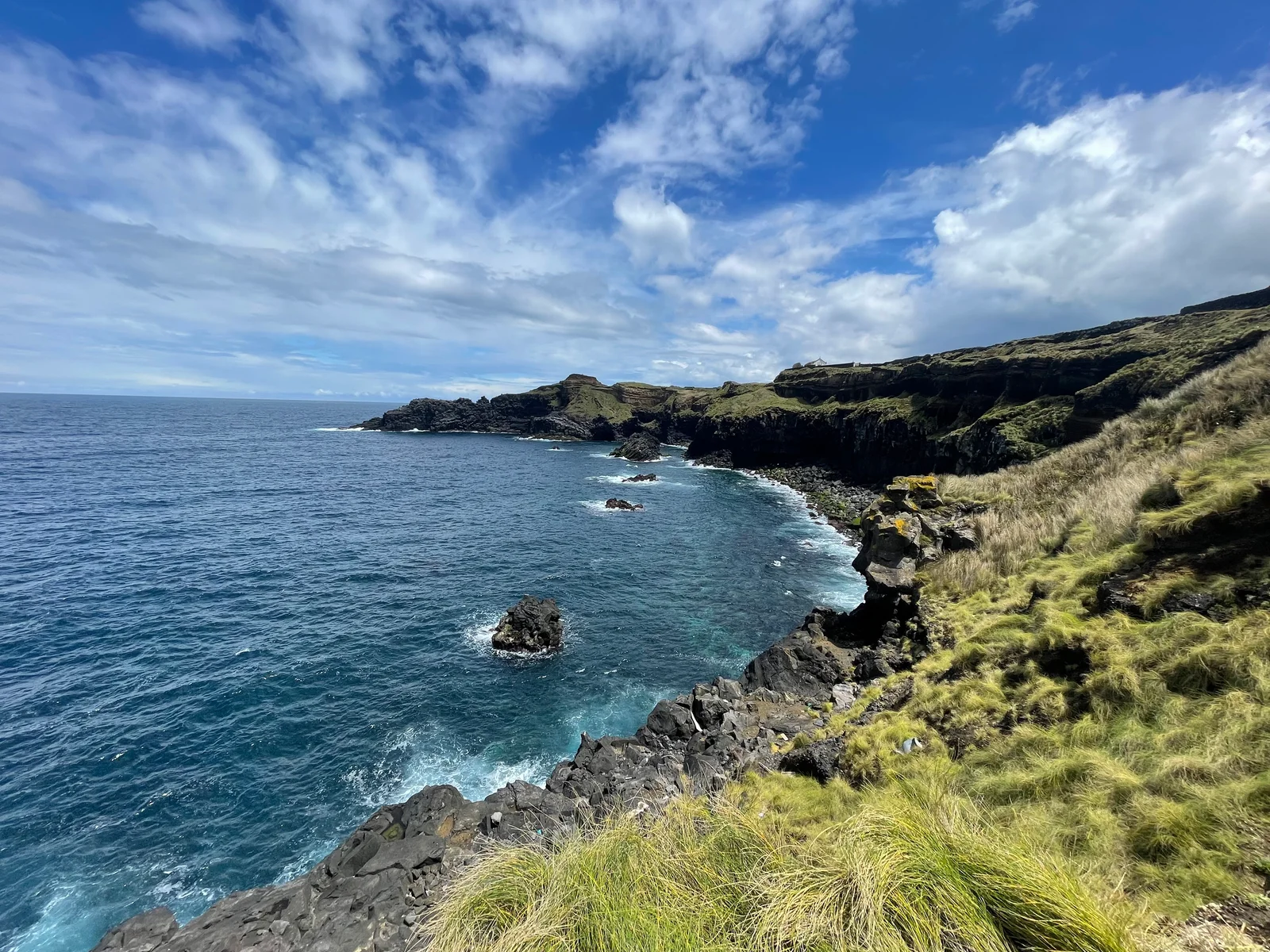 São Miguel's volcanic coastline, with green cliffs and blue sea.